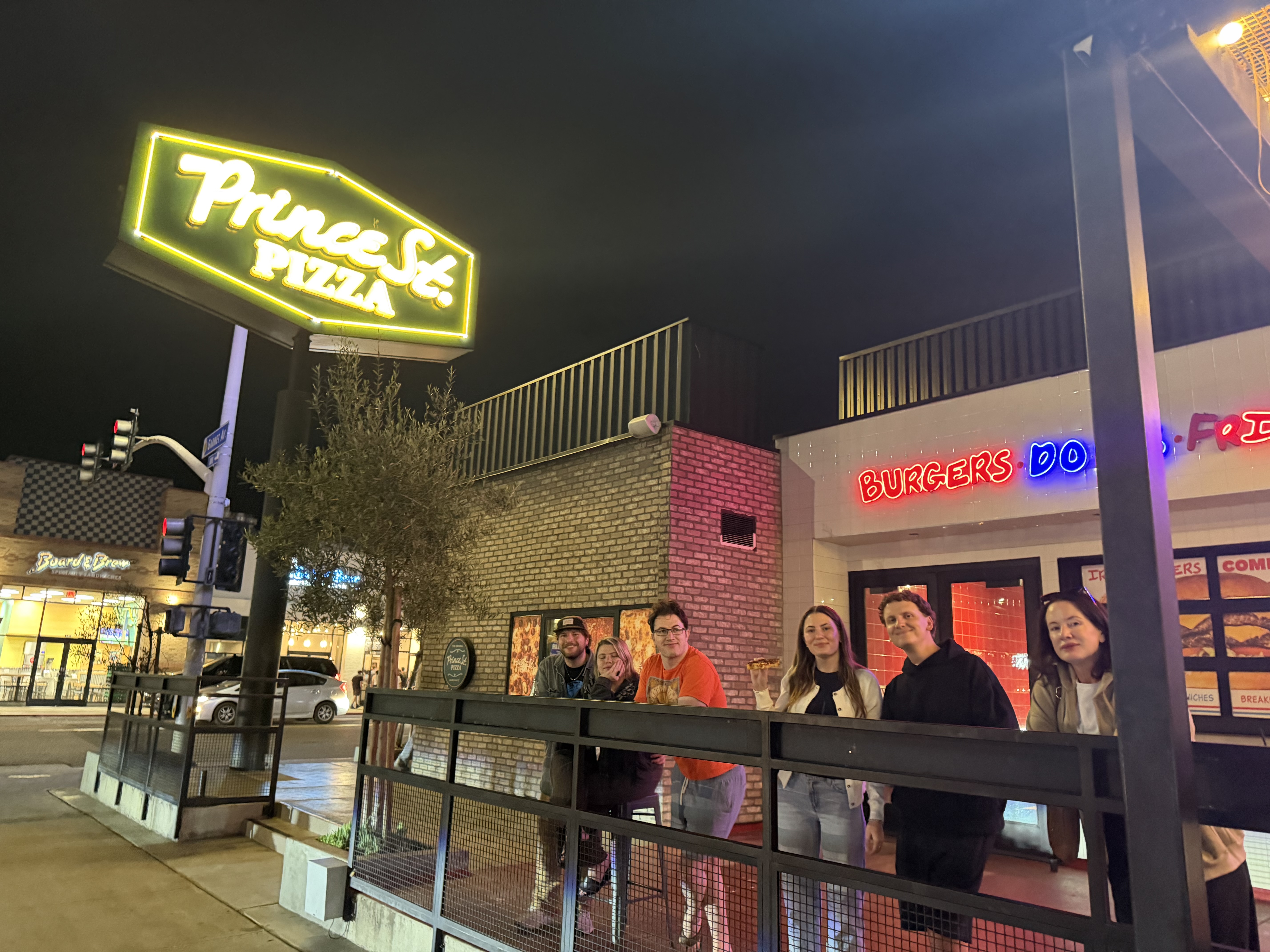 Our group gathered outside Prince St. Pizza in La Jolla at night under the glowing neon sign